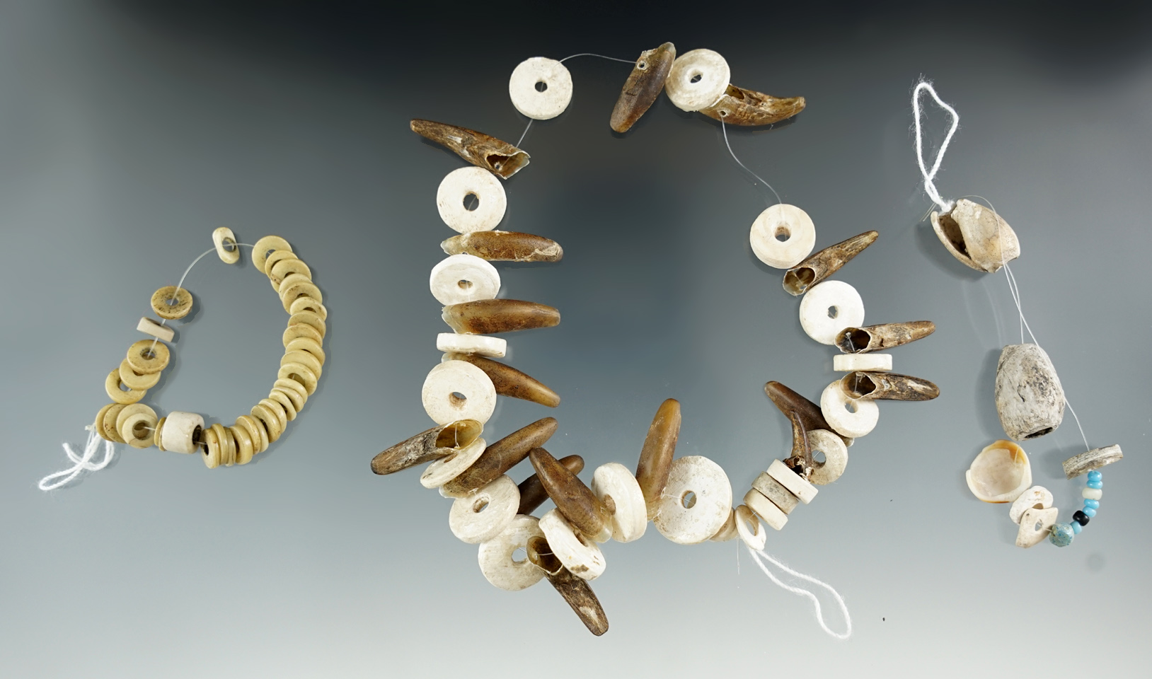 Set of three strands of drilled stone, shell and tooth beads.