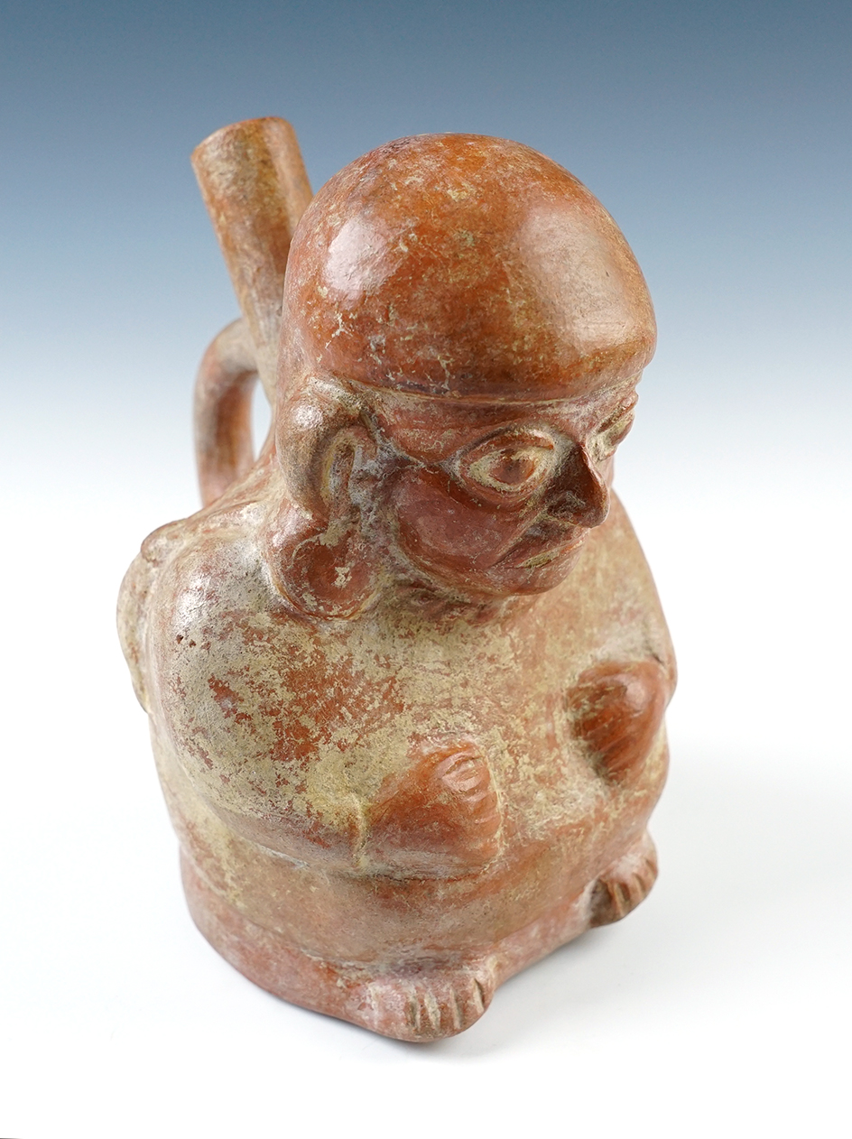 7" tall Moche II - III Seated Human Effigy Bottle depicting a man with ear plugs and bag. 