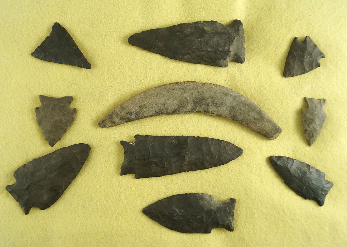 Nice group of nine assorted arrowheads and a 5 3/16" curved, notched and tallied stone pendant